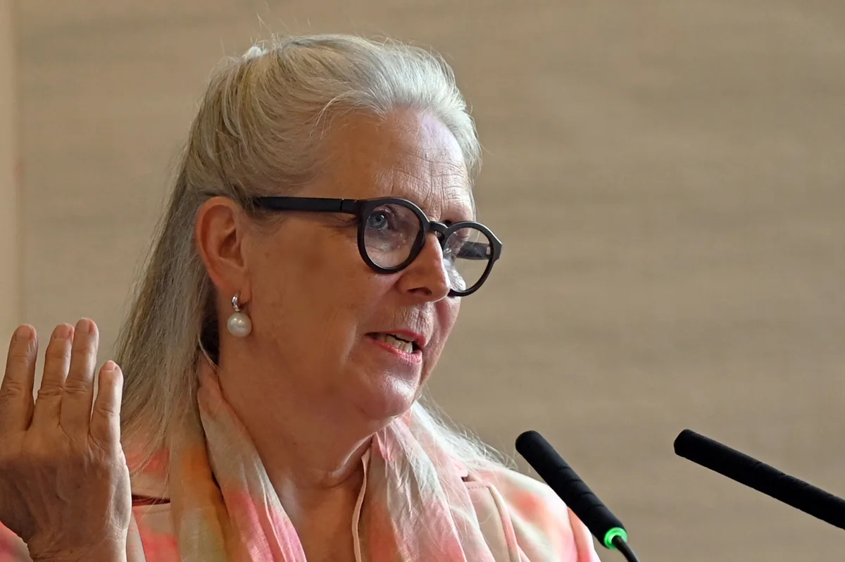 Karin Lenzlinger führte zum zehnten Mal durch eine Generalversammlung der ZO Medien AG. Karin Lenzlinger, Verwaltungsratspräsidentin der ZO Medien AG: Sie trägt ein Kleid in Weiss und Rosa und spricht hinter einem Stehpult. Im Hintergrund sind Holzkisten mit Pflanzen zu sehen.